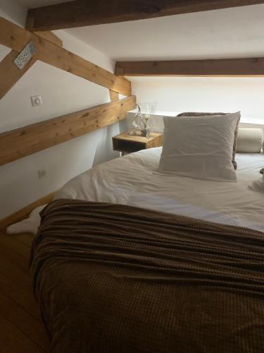 une chambre avec un grand lit avec un plafond en bois dans l'établissement Pasithéa Loft Spa Privatif, à Calais