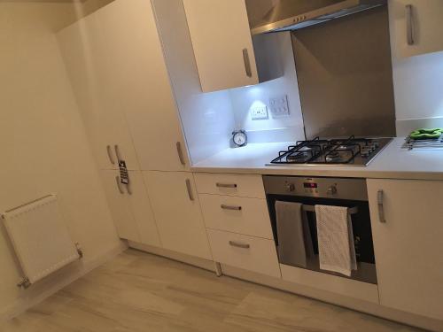 a kitchen with white cabinets and a stove top oven at The Joyland House in Romsey