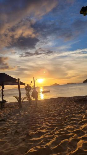 a person standing on a beach at sunset at Mares de Camburizinho in Camburi