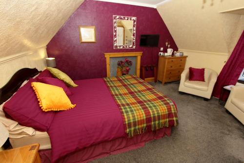 1 dormitorio con cama, espejo y silla en Braeside Guest Rooms, en Portree