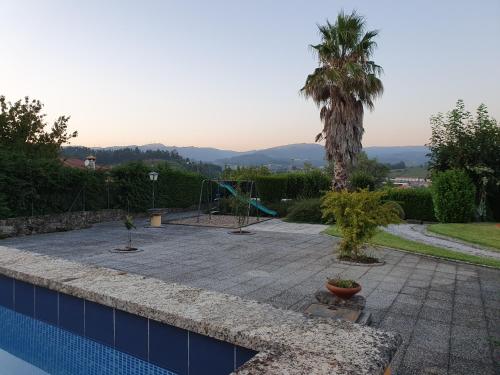 a swimming pool with a palm tree and a playground at Casa dos Chãos in Cabeceiras de Basto