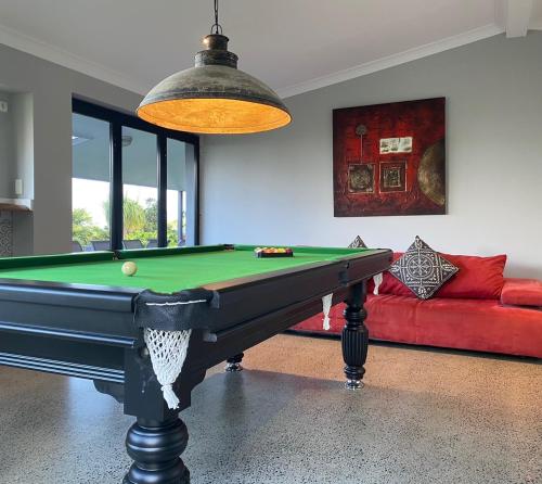 a room with a pool table and a red couch at The Bird House in Mount Tamborine