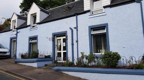 a white house with blue trim on a street at Braeside Guest Rooms in Portree