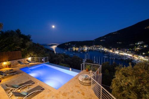 a swimming pool with a view of a harbor at night at Ktima Aniforeli Luxury Villas in Sivota