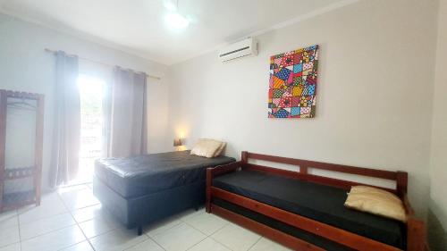 Un dormitorio con dos camas y un cuadro en la pared. en Piscina Aquecida, 5 suítes, Bilhar, Varanda Gourmet, 100mts mar, en Itanhaém