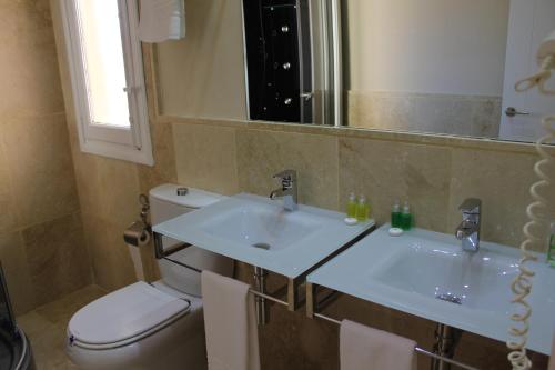 a bathroom with a sink and a toilet and a mirror at Hotel Leonor de Aquitania in Cuenca