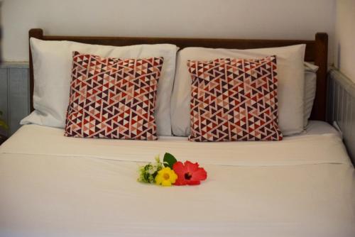 a white bed with two pillows and a flower on it at Leo's Clan Beach Hostel in Paraty