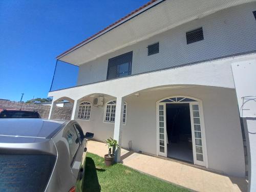 a car parked in front of a white house at Casa 500 metros do mar in Florianópolis