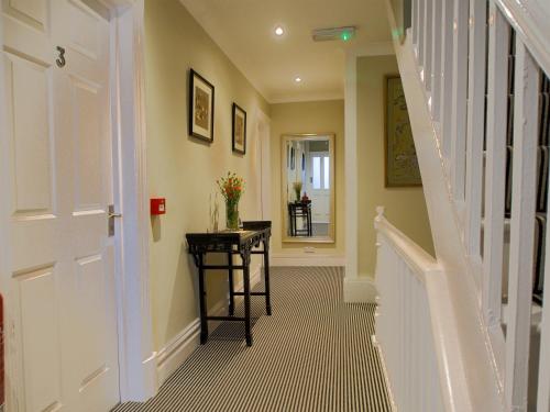 a hallway with a staircase with a table and a door at Riverbank Bed and Breakfast in Llanwrtyd Wells