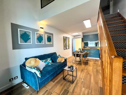 a living room with a blue couch and a table at Le Pétrel Noir - Appartement sur la plage des Roches Noires à Saint-Gilles-les-Bains in Saint-Gilles les Bains