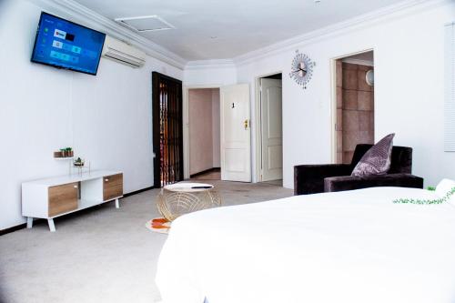 Erima Lodge في جوهانسبرغ: غرفة معيشة مع أريكة وتلفزيون على الحائط