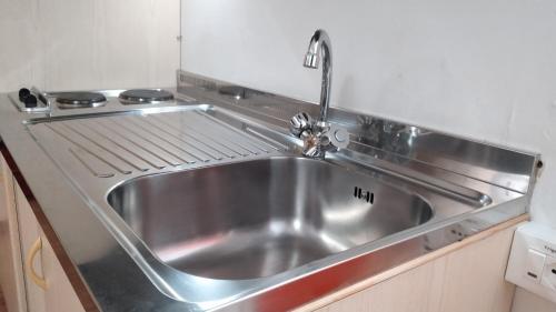un lavandino in acciaio inossidabile in una cucina con piano cottura di GRAYNITE-High Altitude Apartment a Passo del Tonale