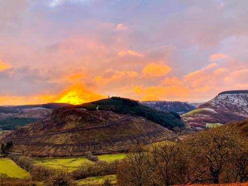 a painting of a hill with a sunset in the background at Riverbank Bed and Breakfast in Llanwrtyd Wells