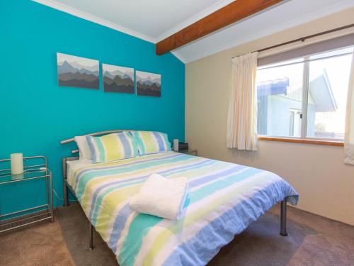 een blauwe slaapkamer met een bed en een raam bij Charvel 1 35 Gippsland Street in Jindabyne
