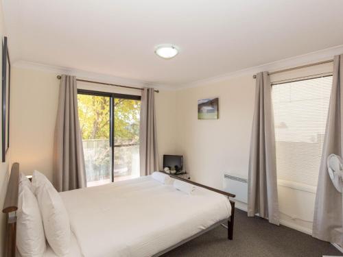 a bedroom with a bed and a large window at Alaska 2 8 Poley Cow Lane in Jindabyne