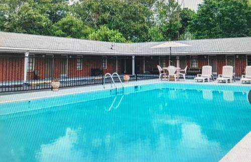 uma grande piscina azul com cadeiras e um guarda-sol em MERRIMAC INN & SUITES em Williamsburg
