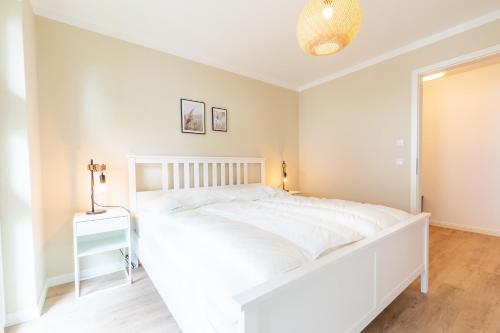 um quarto branco com uma grande cama branca e uma mesa em Strandvilla Meeresblick Wohnung 02 em Boltenhagen