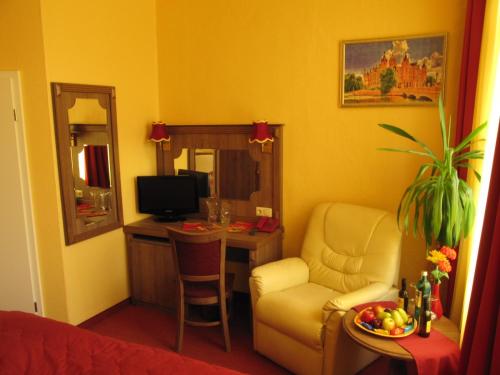 a living room with a chair and a desk with a television at Hotel am Hauptbahnhof in Schwerin
