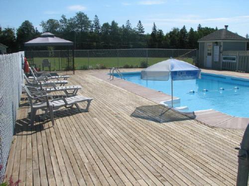 a large swimming pool with chairs and an umbrella at Brudenell Fairway Chalets in Georgetown