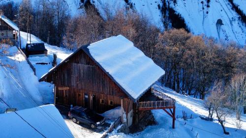 a barn covered in snow with a car parked next to it at Authentique grange savoyarde in Albiez-Montrond