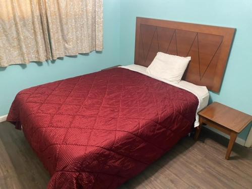 a bedroom with a bed with a red comforter and a table at Mountain Trail Lodge and Vacation Rentals in Oakhurst