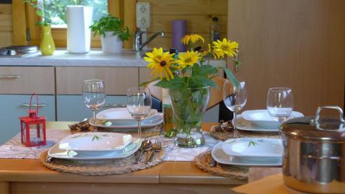 einen Tisch mit Tellern und Gläsern und eine Vase Blumen in der Unterkunft Ferienhaus Natura in Neuruppin