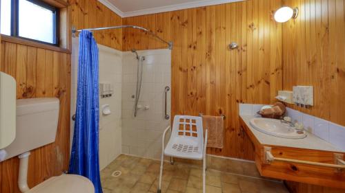 a bathroom with wooden walls and a shower and a sink at Country Roads Motor Inn in Narrandera