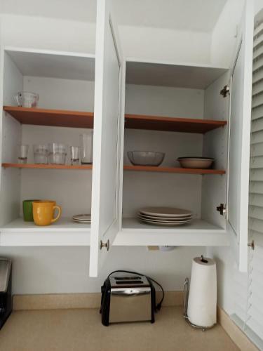 a white cabinet with plates and bowls and dishes at Joy Estate Rooftop Pool n View unit #1 in Falmouth