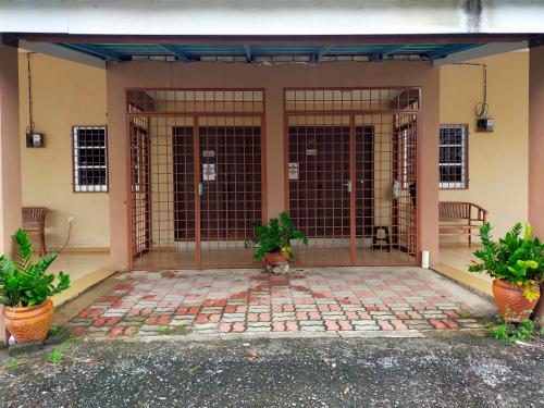 a front door of a house with two potted plants at Homestay Sri Uda A in Alor Setar