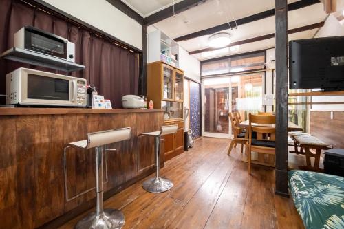 a kitchen with a bar with stools and a microwave at GuestHouse OneWorld Shijo四条京町屋 in Kyoto