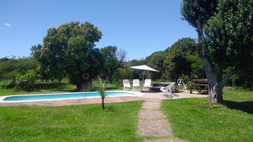 a pool with chairs and a table and an umbrella at Estancia Rincón del San Francisco in Paysandú