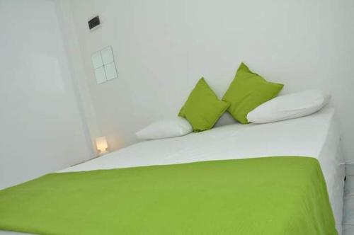 a bed with green and white pillows on it at Viraj's Garden in Tangalle