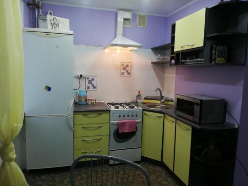 cocina con armarios amarillos y morados y nevera blanca en Apartments on Shmidta Street ( Ozerka), en Dnipro