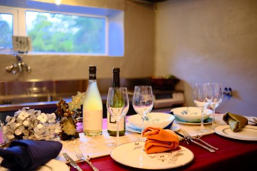 a table with wine glasses and wine bottles on it at ヴィラYukara緑屋 in Nanae