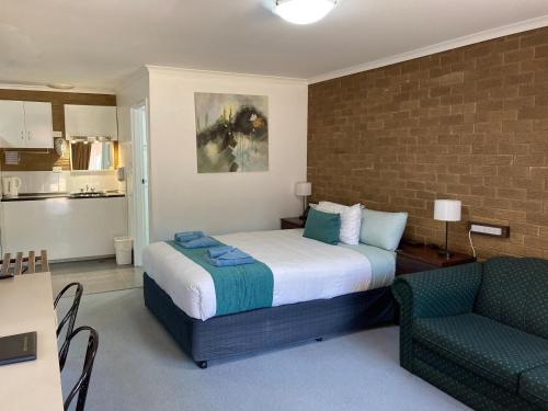 a bedroom with a bed and a couch and a chair at Camellia Motel in Narrandera
