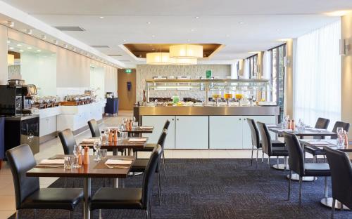 a kitchen with a table, chairs, and a refrigerator at Holiday Inn Parramatta, an IHG Hotel in Sydney