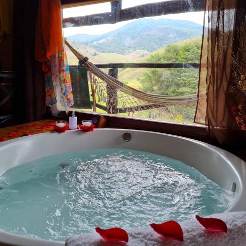 a bath tub filled with water in front of a window at Pousada Vale Monte Azul in Santo Antônio do Pinhal