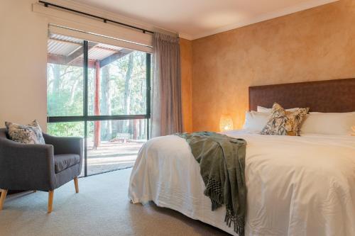 a bedroom with a bed and a window and a chair at Forest Rise Chalets and Lodge in Metricup