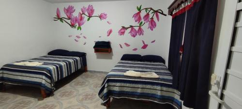 two beds in a room with flowers on the wall at Posada TEO in Xilitla