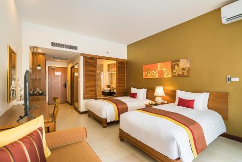 a hotel room with two beds and a living room at Cosy Beach Hotel - SHA Extra Plus in Pattaya South