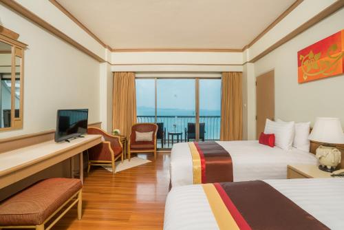 a hotel room with two beds and a television at Cosy Beach Hotel - SHA Extra Plus in Pattaya South