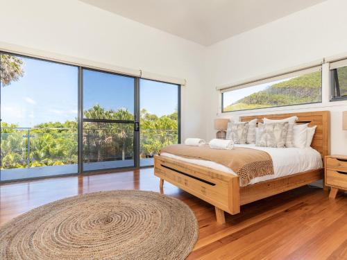 a bedroom with a large bed and large windows at Aiyana in Blueys Beach