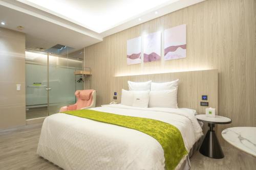 a bedroom with a large bed and a pink chair at 168 Motel-Taoyuan in Taoyuan