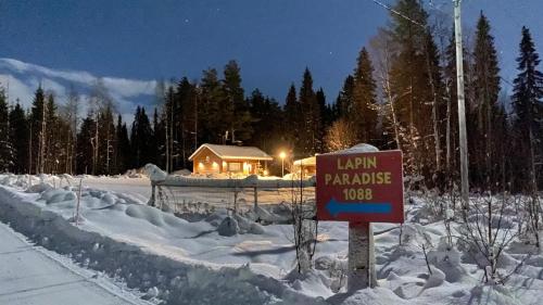 a sign in the snow in front of a house at Lapin Paradise in Rovaniemi