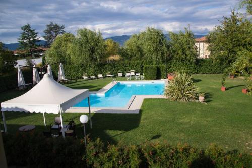 een zwembad in een tuin met een witte parasol bij Room in Holiday house - Apartment in Farmhouse Casolare dei Fiori in Chiesina Uzzanese