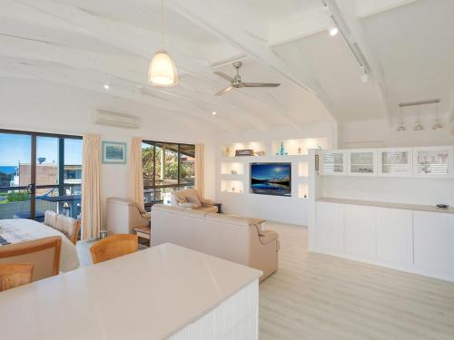 a kitchen and living room with white walls and ceilings at Kianga Parade Beach House in Kianga