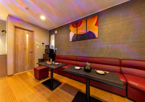 a living room with a red couch and two tables at YADOYA Yumeji in Tokyo