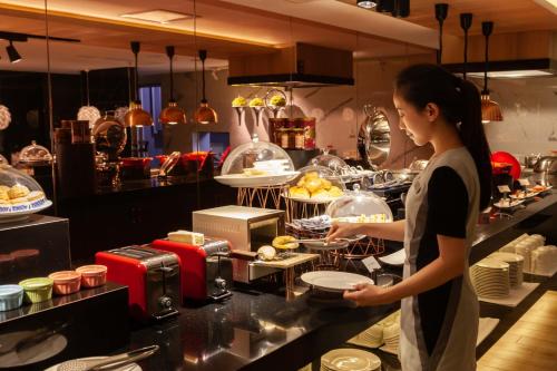 a woman standing in a kitchen preparing food at Chao Motel in Taoyuan