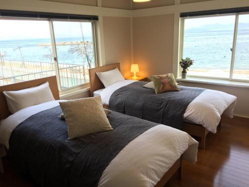 高松市にあるMegijima Beach Apartmentの海の景色を望む客室で、ベッド2台が備わります。