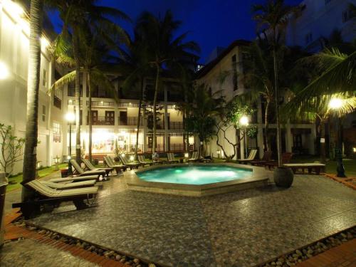 a swimming pool in front of a building at night at Le Huynh Mui Ne Hotel in Mui Ne